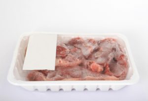 Frozen supermarket groceries meat on white, isolated, copy space, close-up, macro.